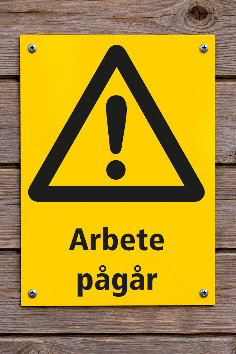 Varningsskylt på trävägg, arbete pågår