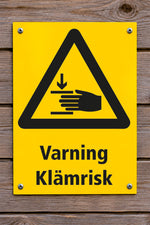 Varningsskylt på trävägg, Klämrisk
